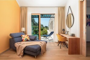 Ein modernes Hotelzimmer mit Schlafsofa, Schreibtisch, Stuhl, großem Spiegel und einer Glastür zum Außenbereich.