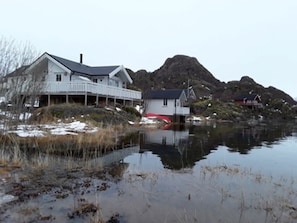 A house by a calm body of water with a mountain in the background.