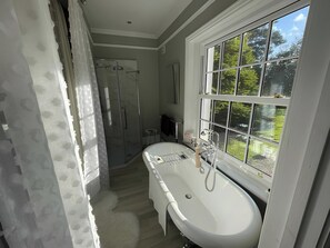 Ein Badezimmer mit großem Fenster, Dusche und Badewanne.