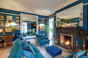 A living room with teal sofas, a fireplace, and a large mirror. - Exquisite Georgian Villa With Hot Tub Dog Friendly (Ross-on-Wye)