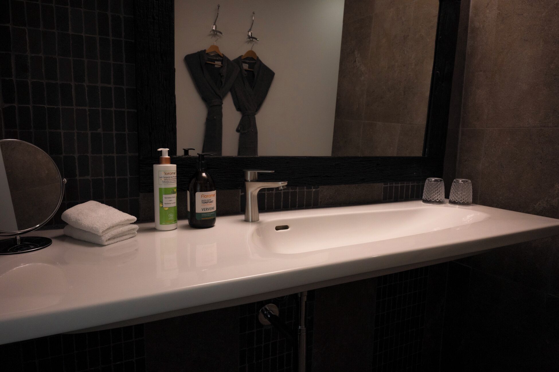 A bathroom with a white sink, a mirror, a bottle of lotion, and a towel.