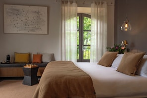 A bedroom with a large bed, a sofa with cushions, a chessboard, a side table, and a window with curtains. - Mas de l'Amarine (St.-Remy-de-Provence)
