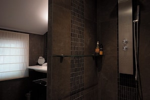 A modern bathroom with a shower, a glass shelf with toiletries, and a towel rack. - Mas de l'Amarine (St.-Remy-de-Provence)