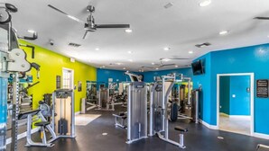 Una palestra con diverse macchine per esercizi, una ventola a soffitto e una parete blu.