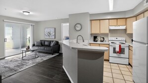 Een moderne keuken met een centraal eiland, een zithoek met een bank en een groot raam.
