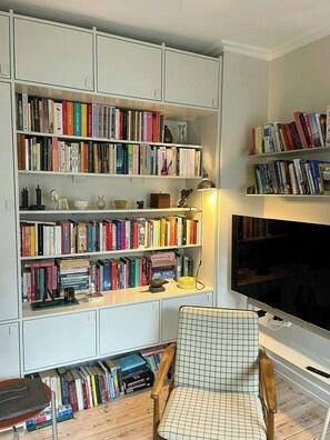 Una sala de estar con una amplia estantería, un televisor y un sillón estampado.