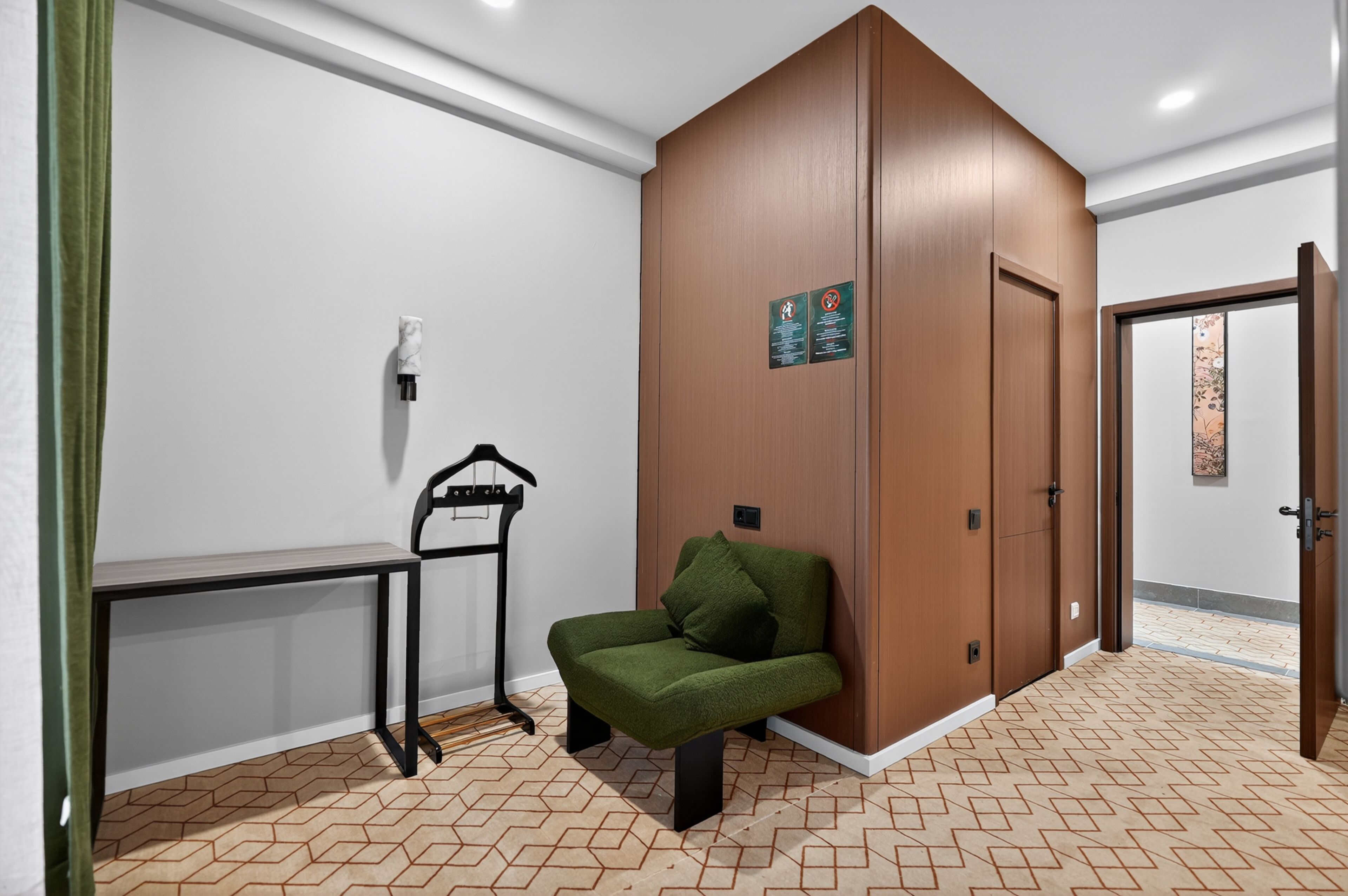 Una habitación con un sofá verde, un aparador de madera, un banco y una puerta con un cartel.
