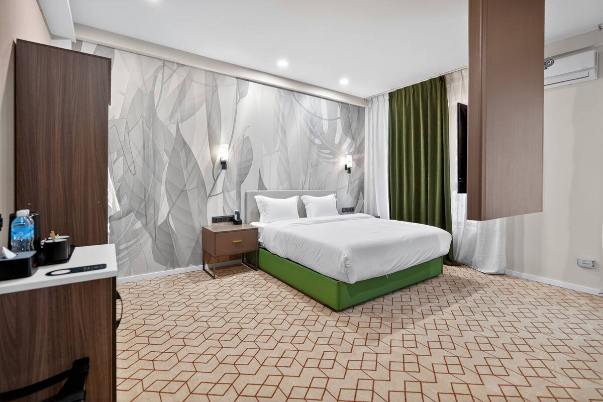 Habitació d'hotel moderna amb un llit gran, un escriptori i un armari.