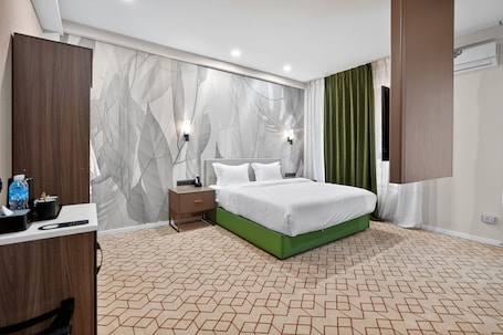A modern hotel room with a large bed, a desk, and a wardrobe.. Nooma Hotel on Koitashsky