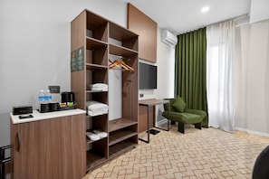 A hotel room with a wardrobe, a desk with a coffee maker, a chair, and a TV. - Nooma Hotel on Koitashsky (Bishkek)