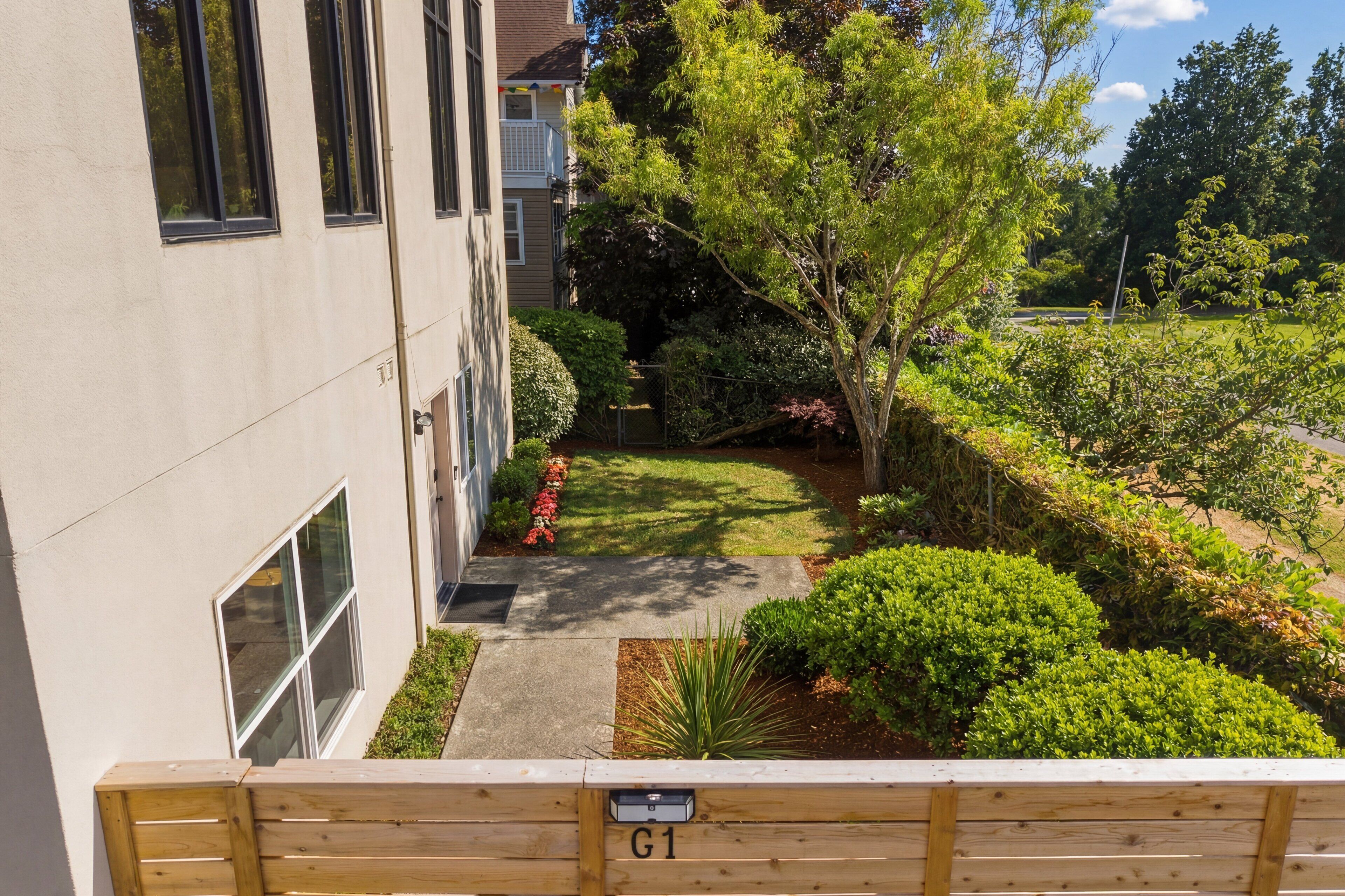 A courtyard with a pathway, a wooden bench, and a building with windows and a door.