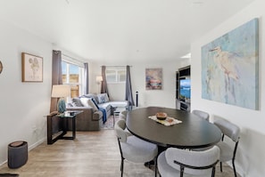 Ein modernes Wohnzimmer mit einem runden Tisch, grauen Sesseln, einem Sofa und einem Bild an der Wand.