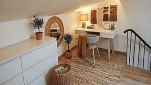 Um quarto de sótão aconchegante com uma escrivaninha, um espelho e uma pequena planta.