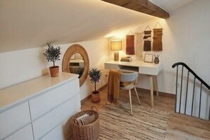 Ein gemütliches Schlafzimmer im Dachgeschoss mit Schreibtisch, Spiegel und einer kleinen Pflanze.