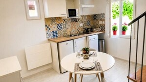Uma cozinha compacta com painel de azulejos, micro-ondas e um espaço de refeições com mesa posta para dois.