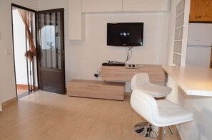 A modern kitchen with a built-in TV, wooden cabinets, a white countertop, and a sliding door. - Apartament Blue Turtle well located, with terrace, close to the beach (Puerto del carmen, Tias)