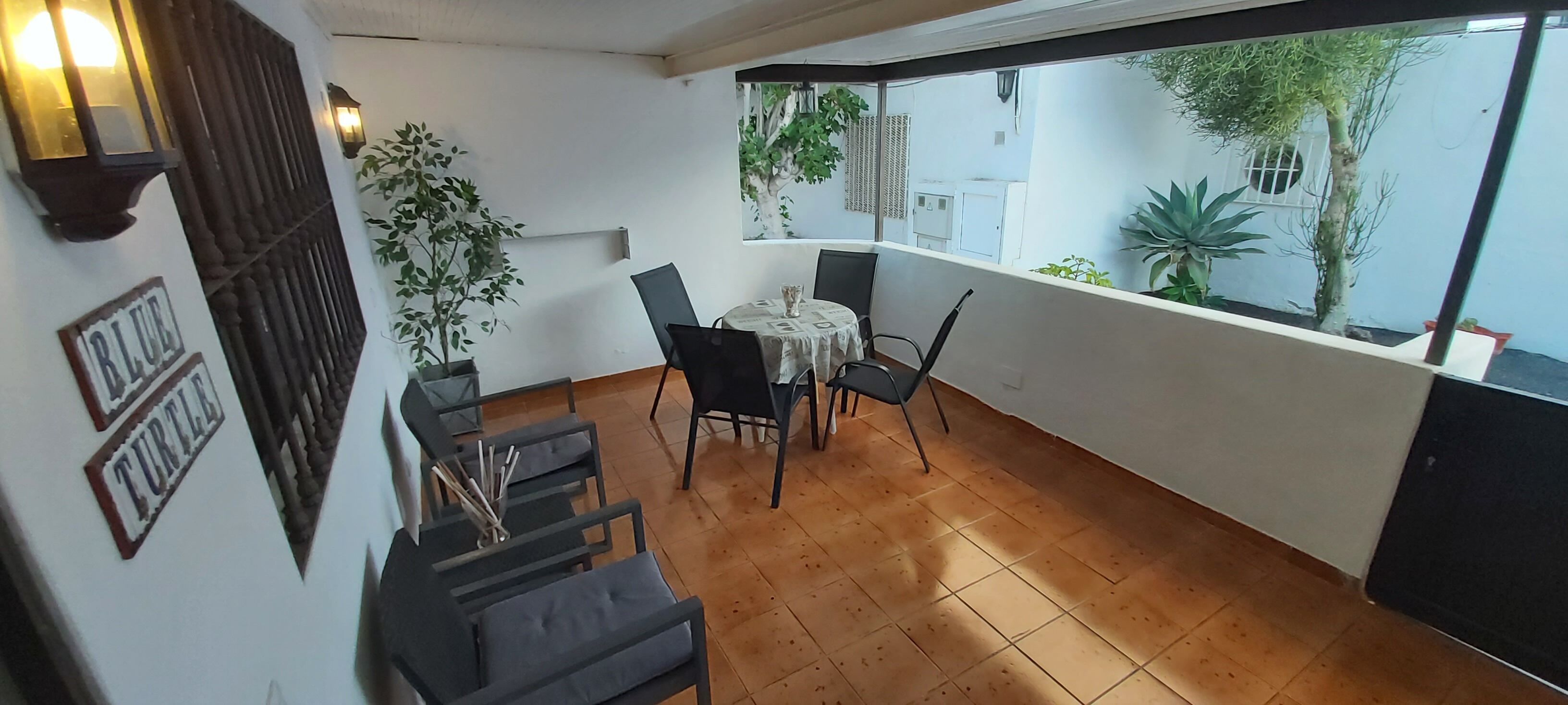A balcony with a table and chairs, a potted plant, and a view of the outside.