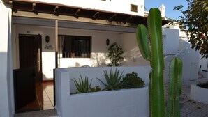 Um edifício branco com uma porta identificada como 'ELN TURTLE', uma janela com cortinas e um cacto em primeiro plano.