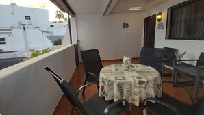 Varanda com mesa, cadeiras, um vaso de planta e vista para edifícios.