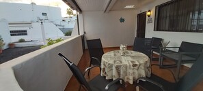Ein Balkon mit Tisch und Stühlen, einem Blumentopf und Blick auf Gebäude.