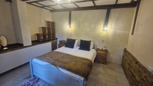 Ein Schlafzimmer mit Bett, Nachttischen, einem Spiegel, einem Heizkörper und einem Holzboden.