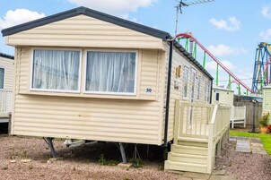 A mobile home with two windows, a number '50' on the side, and a small porch area.