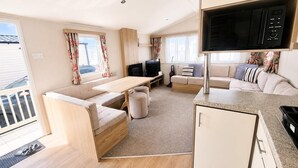 A compact RV interior with a kitchenette, a seating area, and a television. - 3 Bed Caravan - Sleeps 8 - Free Parking (Skegness)