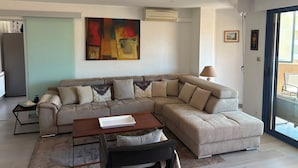 Una sala de estar moderna con un sofá modular, una mesita y un cuadro en la pared.