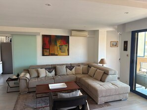 A modern living room with a sectional sofa, a small table, and a painting on the wall. - Bright apartment on 3ᵉ floor - 2 bedrooms and 2 bathrooms (Cavalaire-sur-Mer)