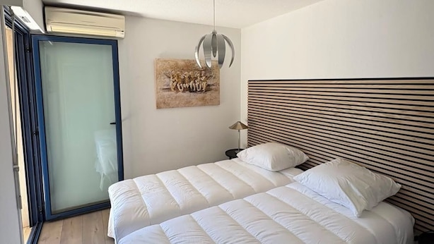 Un dormitorio con una cama grande, un ventilador de techo, una obra de arte colgada en la pared y un ventanal corredero.