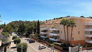 Un edificio residencial de varios pisos con balcones, una zona de estacionamiento y cielo despejado.