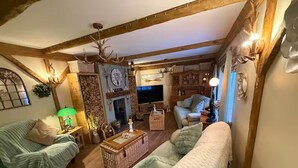 Ein gemütliches Wohnzimmer mit Kamin, Fernseher und Holzboden.