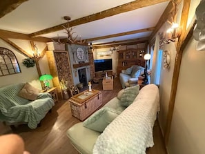 A cozy living room with a fireplace, a television, and a wooden ceiling. - House - Sleeps 6 - Hot Tub (Weymouth)