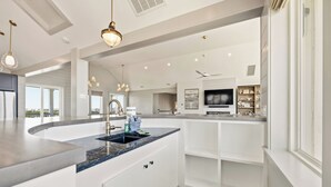 A modern kitchen with a curved island, built-in appliances, and a large window offering a view.