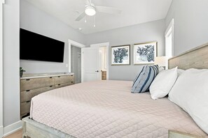 A bedroom with a bed, a dresser, a ceiling fan, and two framed pictures on the wall. - BRAND NEW Luxury Semi-Oceanfront in Kill Devil Hills Seaduction (Kill Devil Hills)
