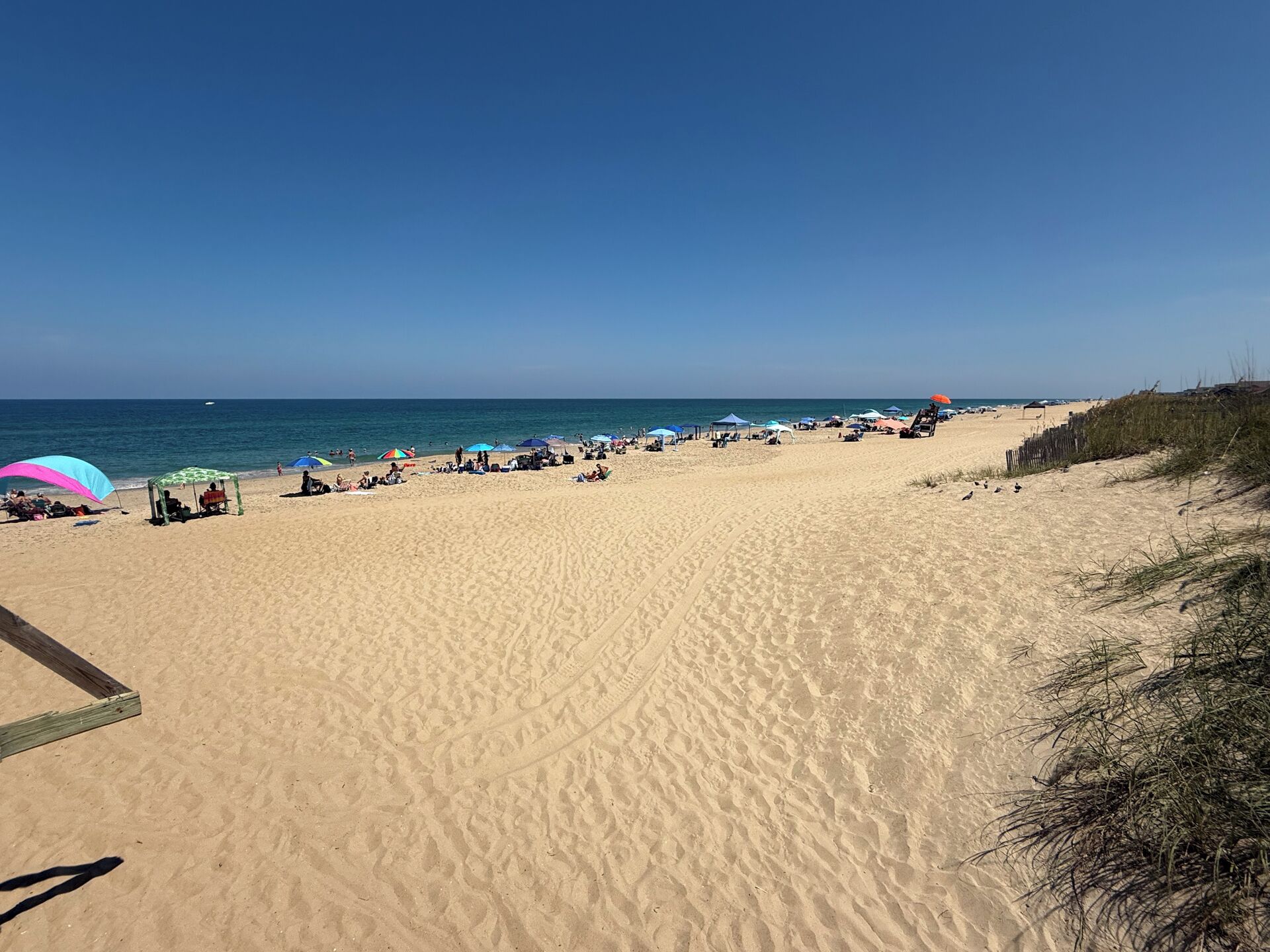 Une vaste plage de sable, parsemée de parasols et fréquentée par de nombreuses personnes.