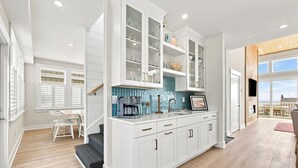 Una cocina moderna con armarios blancos, salpicadero de azulejos y un amplio ventanal con vistas al exterior.