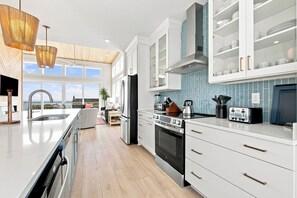 Eine moderne Küche mit einer großen Kochinsel, Edelstahlgeräten und Blick ins Freie.