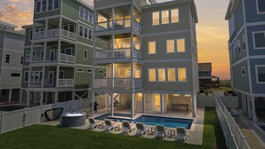 Un edificio residencial de varios pisos con balcones, piscina y mobiliario de exterior.