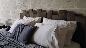 Ein Bett mit gemustertem Überwurf, ein Kopfteil aus Holzbalken und eine Lampe auf einem Nachttisch.