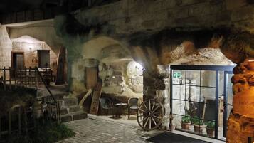 A historic building with stone walls, a wooden door, a wheelchair, and a sign reading 'Hospitality.'