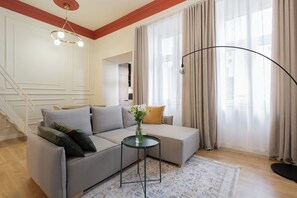 A modern living room with a grey sectional sofa, a small round table with a vase, and a floor lamp. - Native Apartments Węgierska 10  (Kraków)