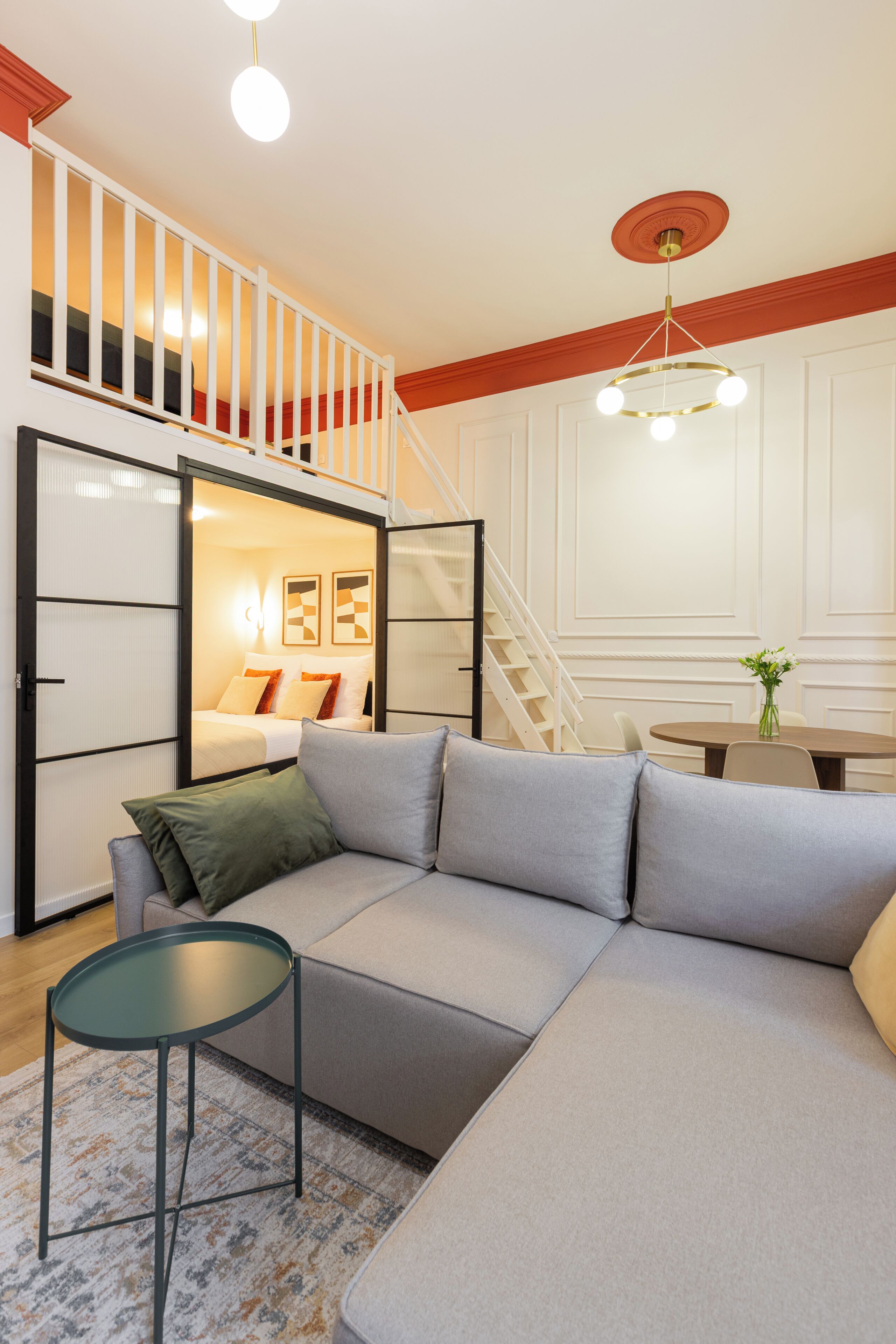 A modern living room with a sectional sofa, a small round table, and a staircase leading to an upper level.