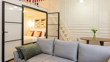 A modern living room with a sectional sofa, a small round table, and a staircase leading to an upper level.