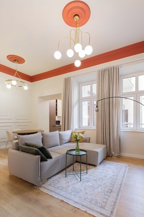 A modern living room with a sectional sofa, a round coffee table, and a large window with curtains. - Native Apartments Węgierska 10  (Kraków)