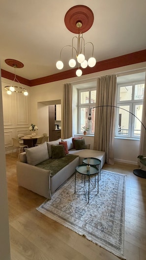 A modern living room with a sectional sofa, a dining table, and a kitchen area. - Native Apartments Węgierska 10  (Kraków)