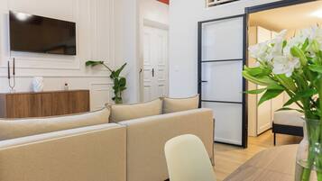 A modern living space with a sofa, a dining table, and a kitchen area.
