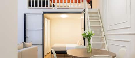 Un intérieur moderne comprenant un coin repas, un escalier et une chambre en mezzanine.