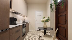 Una cocina compacta con electrodomésticos modernos, una mesa de comedor con un florero y un suelo estampado.