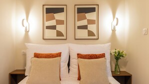 Habitación de hotel con cama, dos lámparas de pared y un florero con flores.